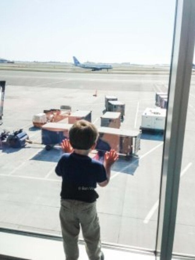 Child looking out of airport window at plane