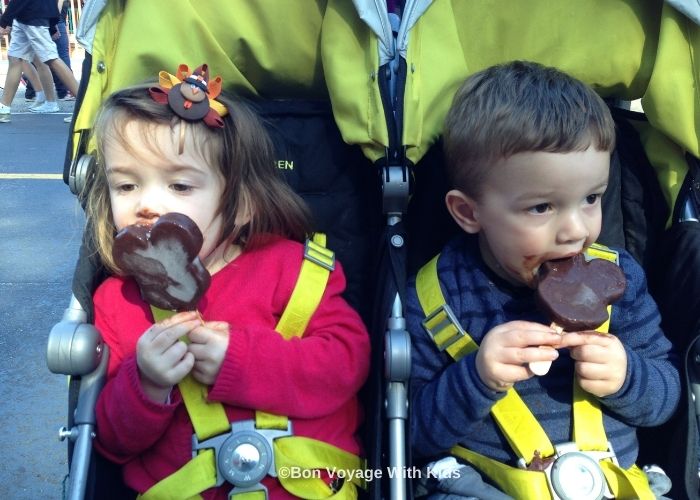 two kids in a a stroller eating a MIckey icecream
